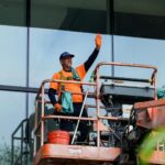 Darbuotojai dėvi apsauginius darbo rūbus industrinėje aplinkoje, pabrėžiant saugumą ir patogumą