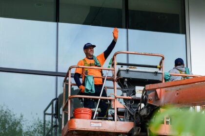 Darbuotojai dėvi apsauginius darbo rūbus industrinėje aplinkoje, pabrėžiant saugumą ir patogumą