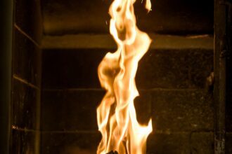 Modernus židinys stilingame interjere su kokybiška dūmų šalinimo sistema.